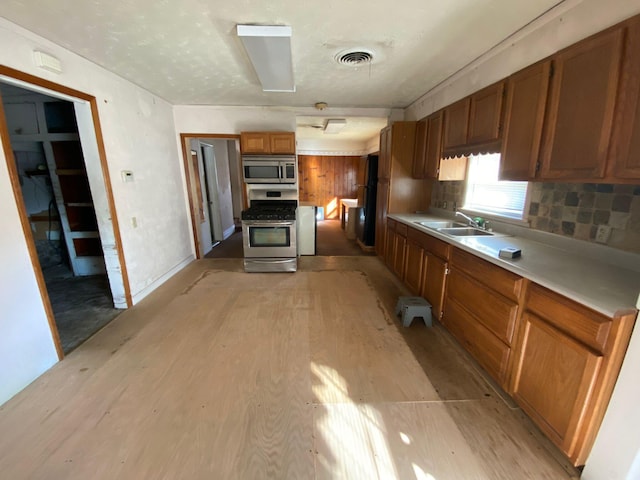 kitchen with decorative backsplash, light wood-type flooring, stainless steel appliances, and sink