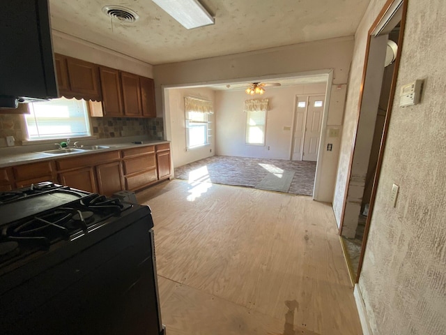 kitchen featuring decorative backsplash, plenty of natural light, black range, and sink