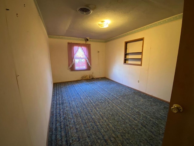 spare room featuring built in shelves and a textured ceiling