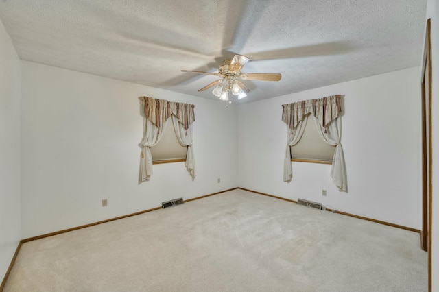 carpeted spare room featuring a textured ceiling and ceiling fan