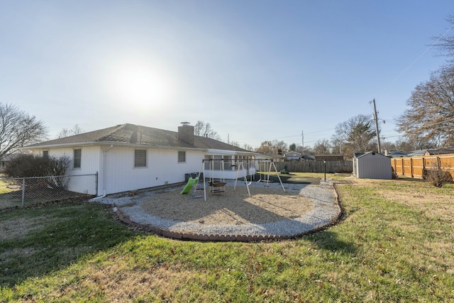 back of house featuring a playground, a yard, and a storage shed