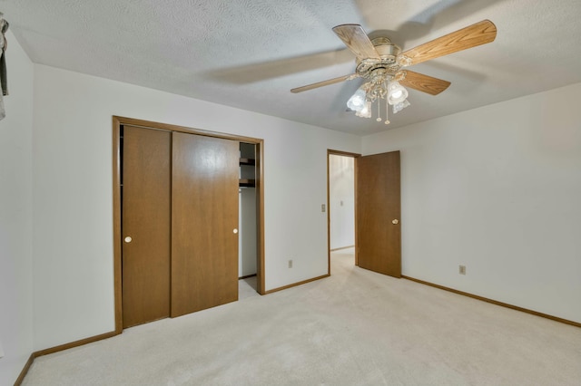 unfurnished bedroom with a textured ceiling, ceiling fan, light carpet, and a closet