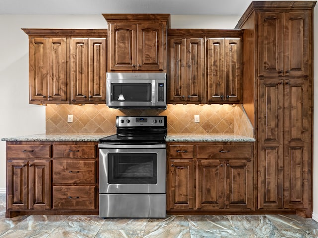 kitchen featuring stainless steel appliances, light stone counters, and tasteful backsplash