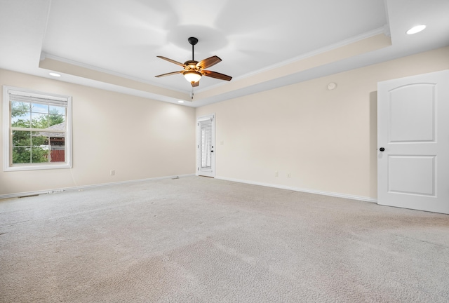 carpeted empty room featuring a tray ceiling, ceiling fan, and ornamental molding