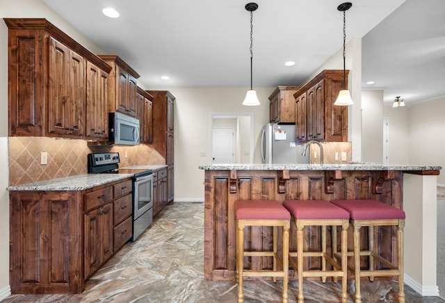 kitchen with light stone counters, backsplash, decorative light fixtures, a kitchen bar, and appliances with stainless steel finishes