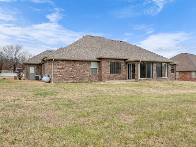 rear view of property featuring a lawn and central AC