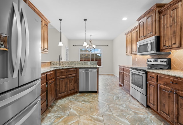 kitchen featuring sink, stainless steel appliances, light stone counters, a chandelier, and decorative light fixtures