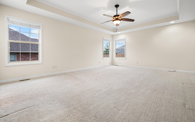 carpeted empty room featuring a tray ceiling, ceiling fan, and crown molding