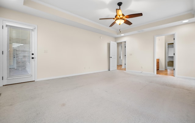 carpeted empty room with a raised ceiling, crown molding, and ceiling fan