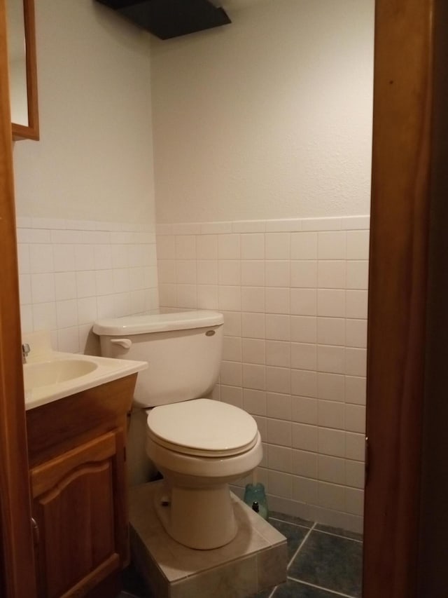 bathroom with tile patterned floors, vanity, tile walls, and toilet