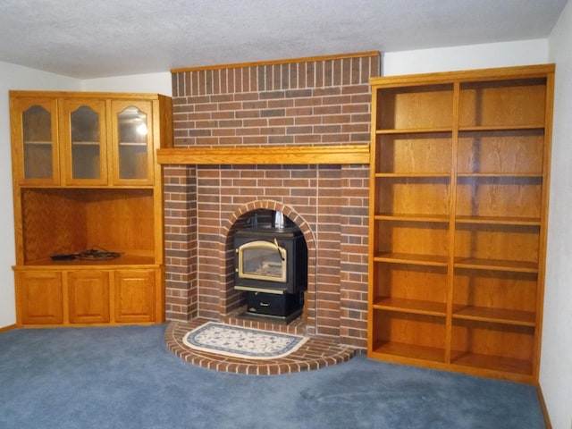 unfurnished living room featuring built in shelves, dark carpet, and a wood stove