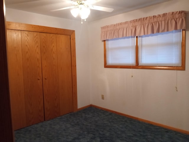 unfurnished bedroom with dark colored carpet, ceiling fan, and a closet