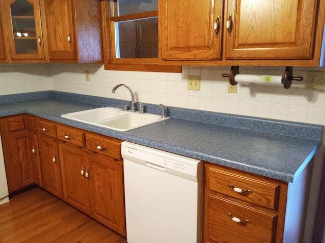 kitchen with white dishwasher, backsplash, sink, and hardwood / wood-style flooring