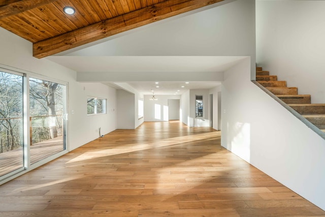 unfurnished living room with beam ceiling, an inviting chandelier, wood ceiling, and light wood-type flooring