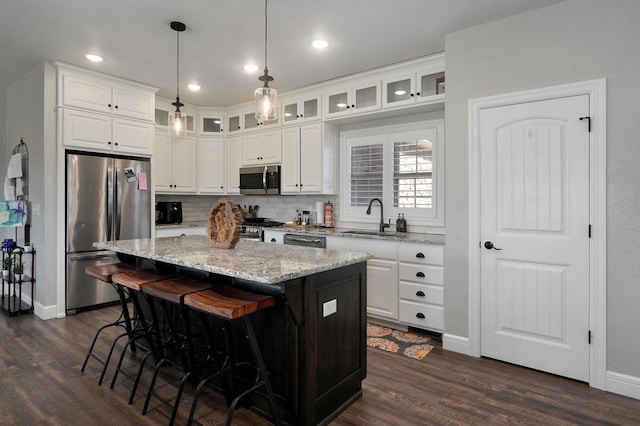 kitchen with white cabinets, decorative light fixtures, a center island, and stainless steel appliances