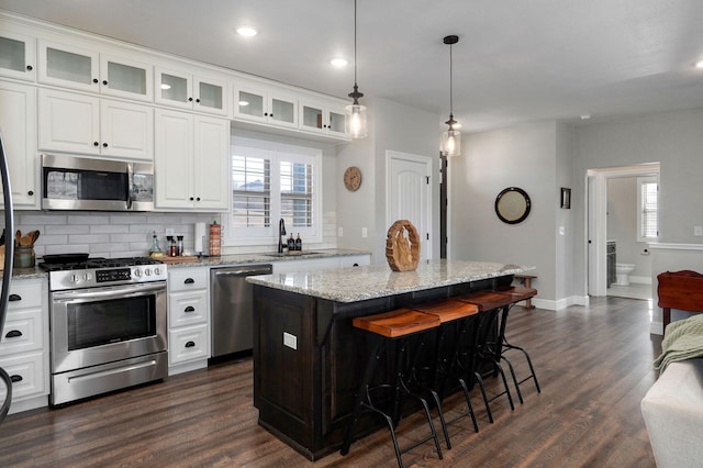 kitchen with backsplash, a kitchen breakfast bar, dark hardwood / wood-style floors, appliances with stainless steel finishes, and a kitchen island