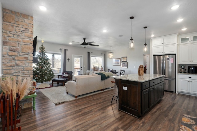 kitchen featuring stainless steel fridge, a kitchen breakfast bar, ceiling fan, a center island, and white cabinetry