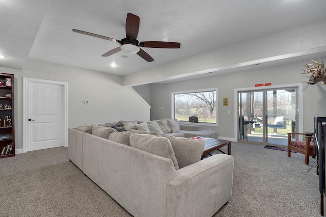 living room featuring carpet flooring, a textured ceiling, and ceiling fan