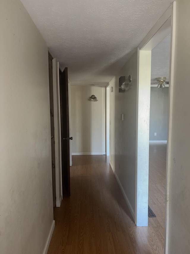 hallway featuring dark wood-type flooring and a textured ceiling