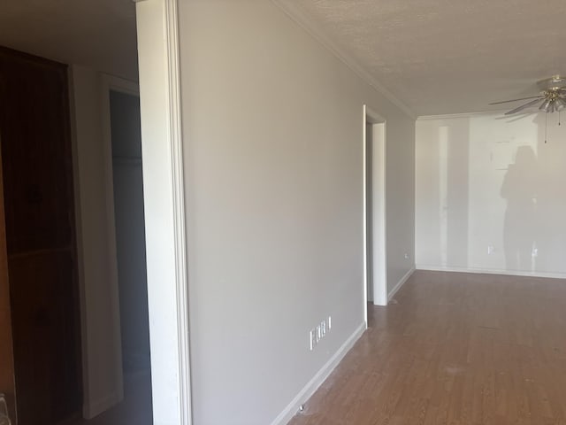 hallway with hardwood / wood-style floors, ornamental molding, and a textured ceiling