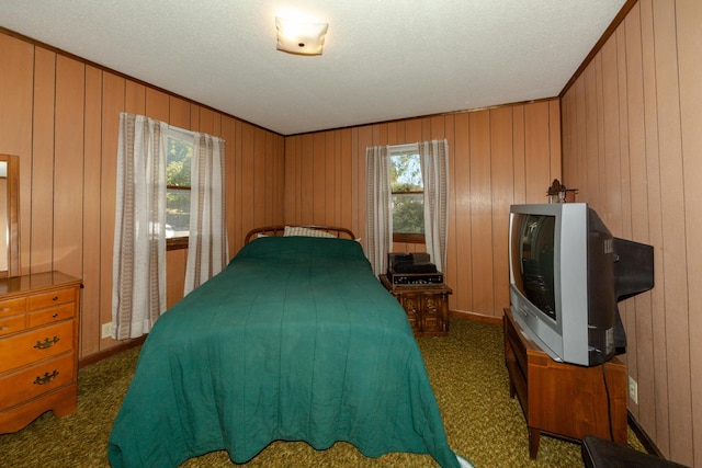 bedroom with multiple windows, wooden walls, dark carpet, and a textured ceiling