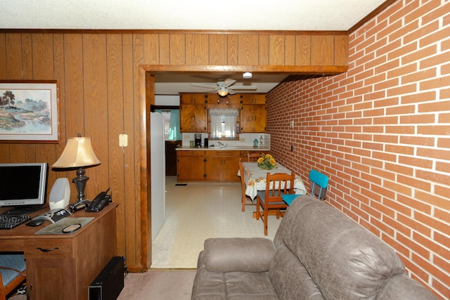 living room featuring sink, ceiling fan, wooden walls, and brick wall