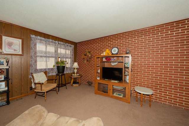 carpeted living room featuring wood walls and brick wall