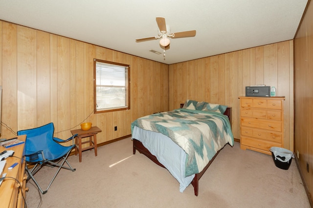 bedroom with ceiling fan, wood walls, and light colored carpet