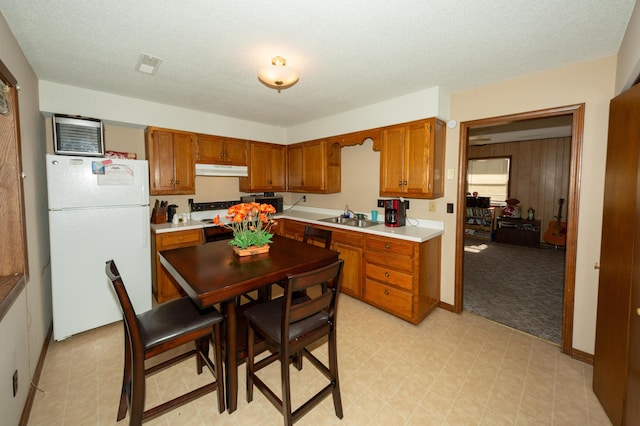 kitchen with wood walls, white refrigerator, sink, and a textured ceiling