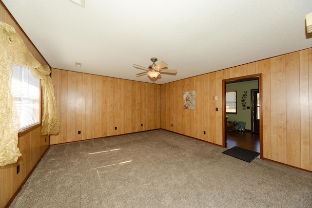 spare room featuring ceiling fan, light colored carpet, and wooden walls