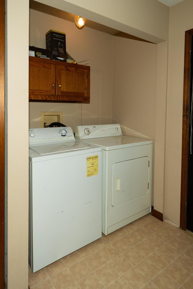 clothes washing area with washing machine and clothes dryer and cabinets