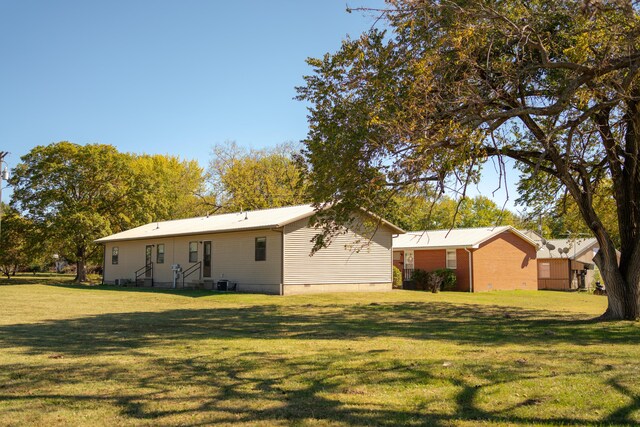 rear view of property featuring central AC and a lawn