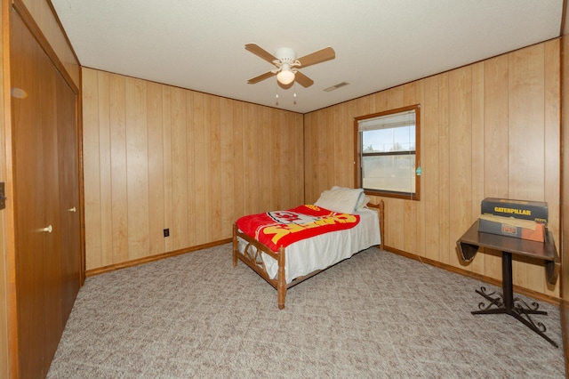 carpeted bedroom with ceiling fan and wooden walls