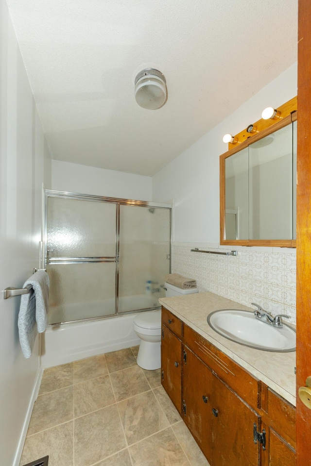 full bathroom featuring decorative backsplash, vanity, toilet, and bath / shower combo with glass door