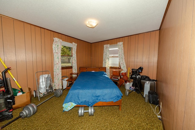 bedroom featuring carpet flooring, a textured ceiling, and wooden walls