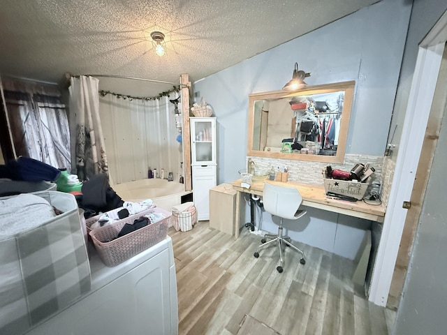 interior space with built in desk, a textured ceiling, and light hardwood / wood-style floors