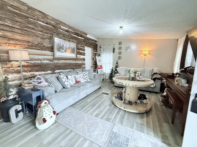 living room featuring wood walls, wood-type flooring, and a textured ceiling