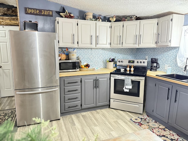 kitchen with white cabinets, stainless steel appliances, gray cabinets, and sink