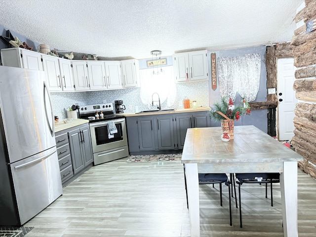 kitchen featuring gray cabinetry, sink, stainless steel appliances, and a textured ceiling