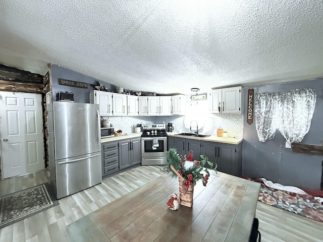 kitchen featuring gray cabinetry, backsplash, sink, and stainless steel appliances