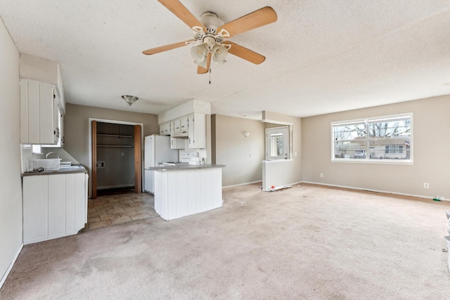 unfurnished living room with light carpet, a textured ceiling, and ceiling fan