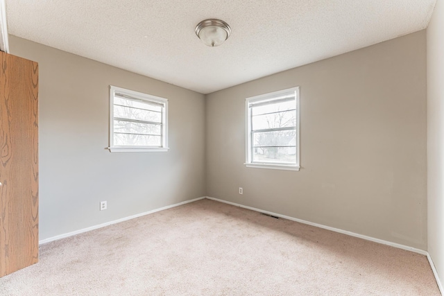 carpeted spare room with a textured ceiling