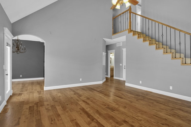 unfurnished living room featuring hardwood / wood-style floors, ceiling fan with notable chandelier, and a high ceiling