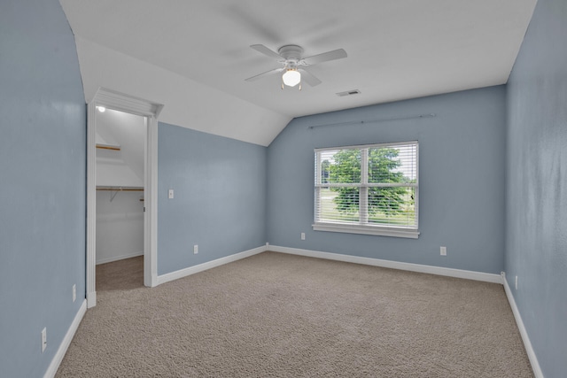 unfurnished bedroom featuring carpet flooring, a spacious closet, ceiling fan, lofted ceiling, and a closet