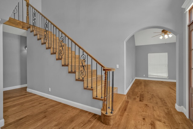 stairway with wood-type flooring and ceiling fan