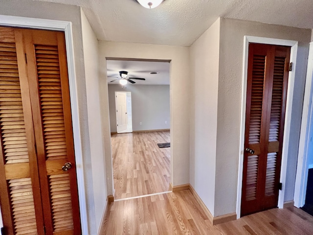 hall featuring a textured ceiling and light hardwood / wood-style flooring