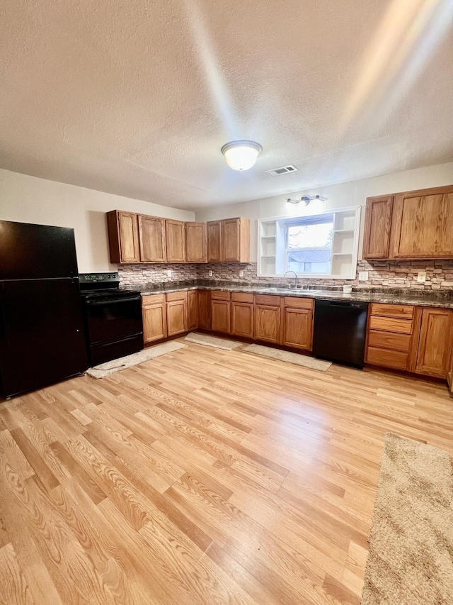 kitchen featuring black appliances, sink, a textured ceiling, and light hardwood / wood-style flooring