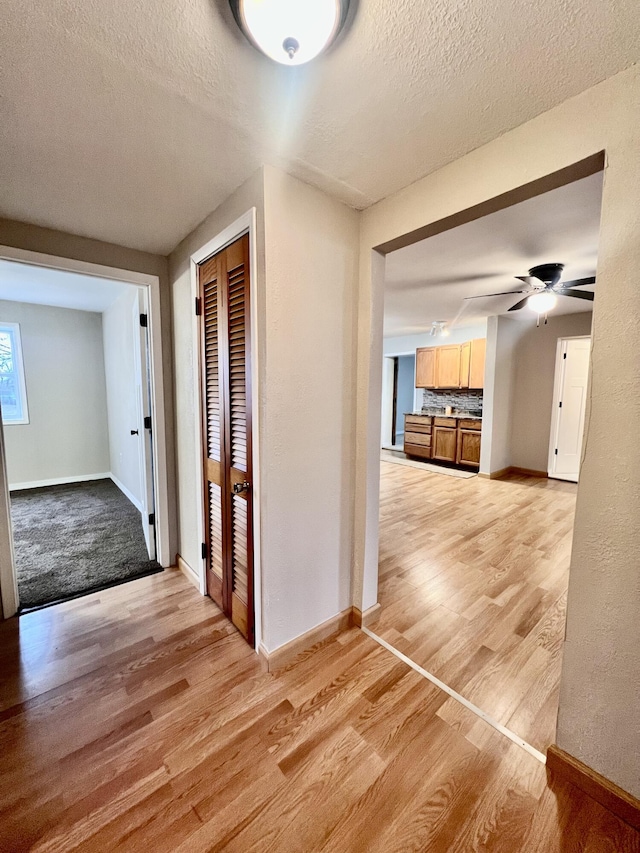 hallway featuring light hardwood / wood-style floors and a textured ceiling