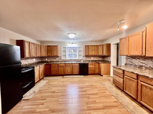 kitchen featuring decorative backsplash, a textured ceiling, sink, black appliances, and light hardwood / wood-style floors