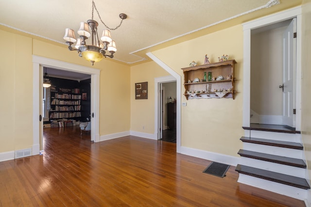 interior space with dark hardwood / wood-style flooring, an inviting chandelier, and ornamental molding